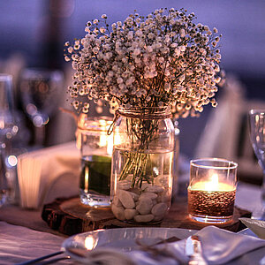 Diverse Gläser, Kerzen und Blumen auf dem Tisch