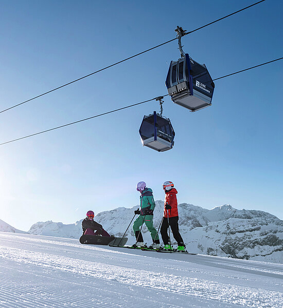 Zwei Skifahrer und ein Snowboarder auf der Skipiste