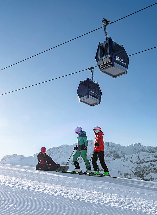 Zwei Skifahrer und ein Snowboarder auf der Skipiste