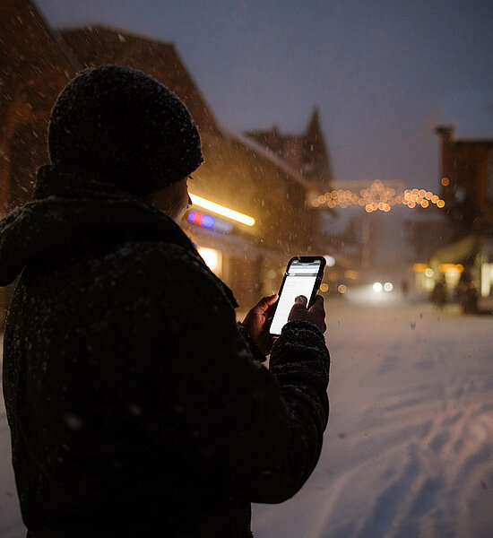 Frau mit Handy steht im Dunkeln