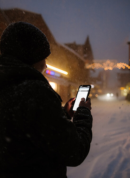 Frau mit Handy steht im Dunkeln