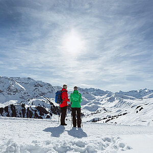 Berglandschaft und ein Mann und eine Frau beim Winterwandern
