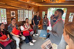 Eine Person erklärt den Gästen die Scherenschnitte im Chalet.